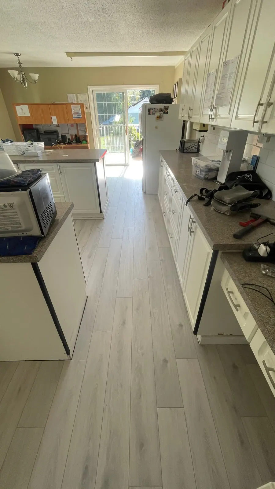 Hardwood flooring through a white kitchen, installed by Becker Flooring in Kelowna